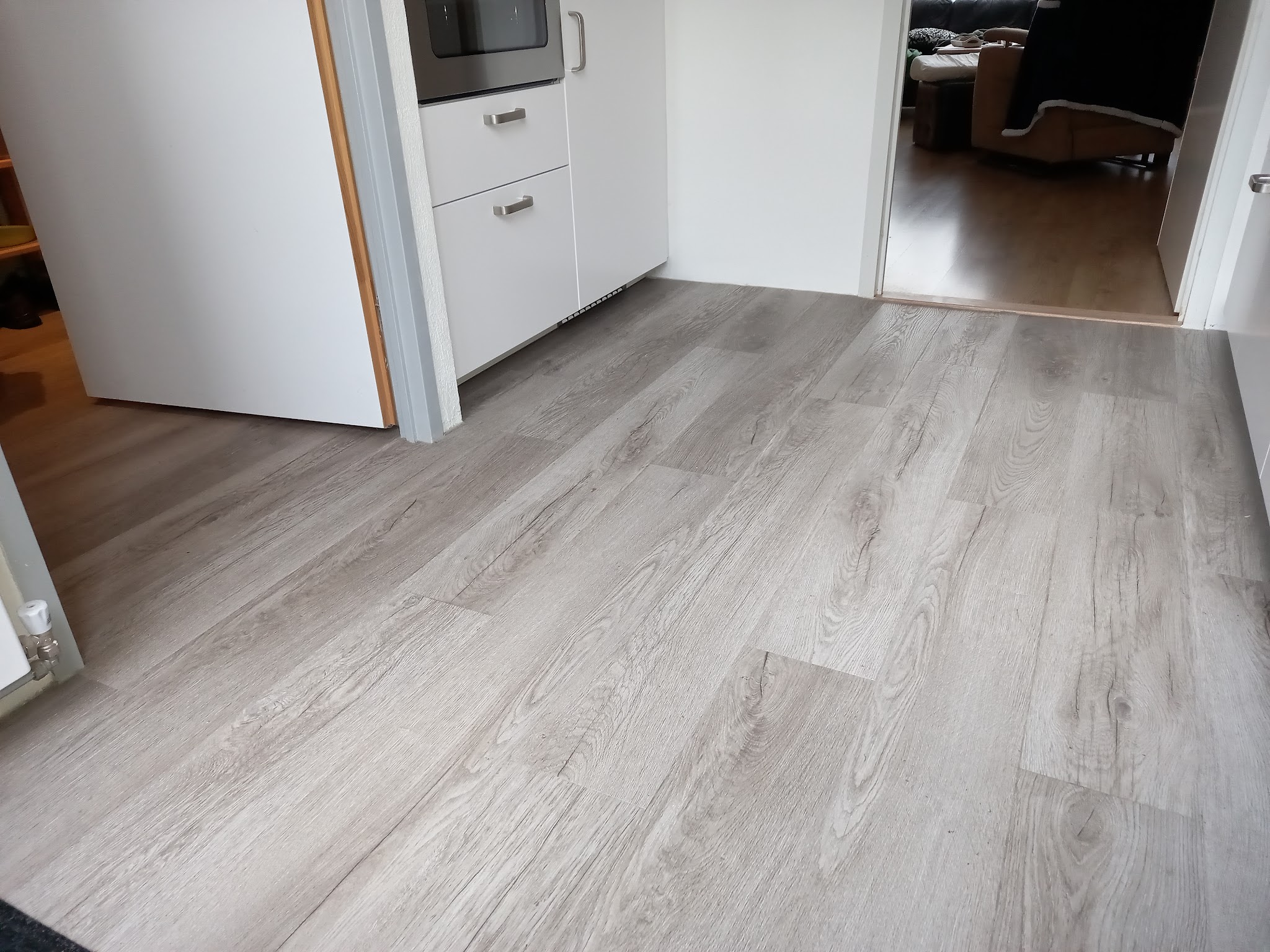 Grijze eikenlook plankvloer in een kleine keuken, doorlopend naar de woonkamer